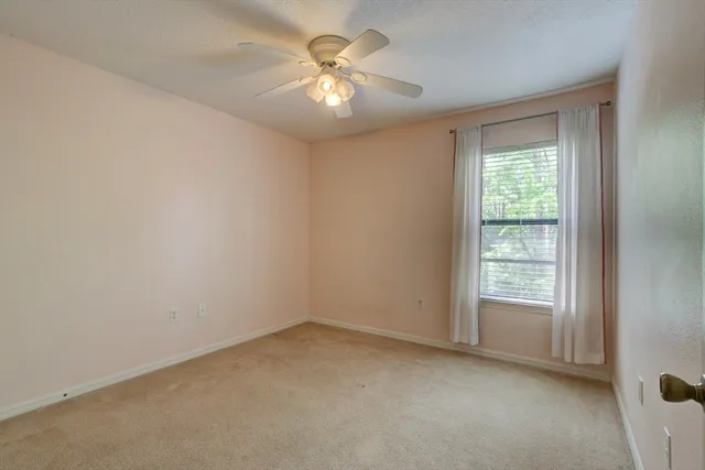 an empty room with a window and a fan
