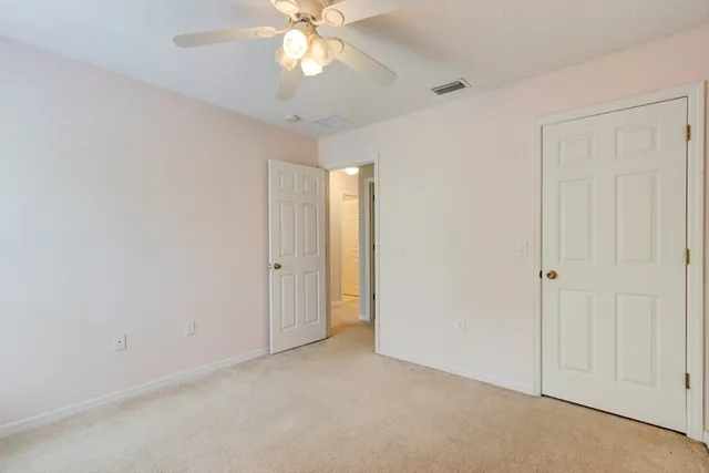 an empty room with a chandelier fan and closet area