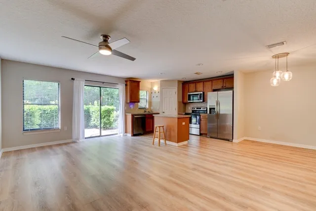 a view of an empty room with wooden floor and a kitchen