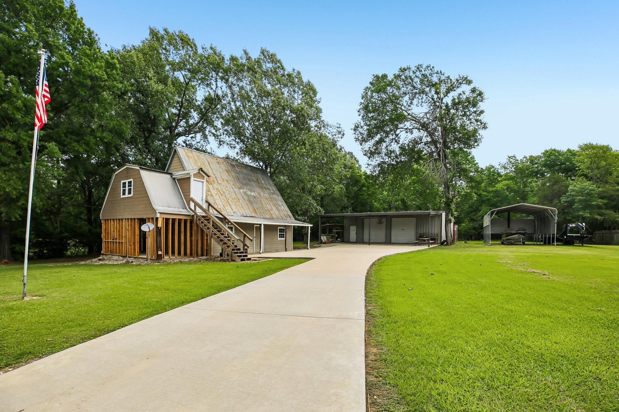 164 Frank Road Trinity, TX 75862 - Photo 12 of 20 12. An inviting front view of the main home, highlighting the classic barn-style architecture and durable metal roof. You'll notice the expansive concrete pad—perfect for easy maintenance and plenty of guest parking.