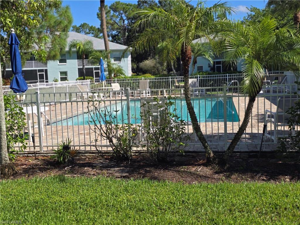 5737 Whitaker Road, Unit C104 Naples, FL 34112 - Photo 7 of 35 Community swimming pool with surrounding paver deck, white metal fencing, and mature palm trees