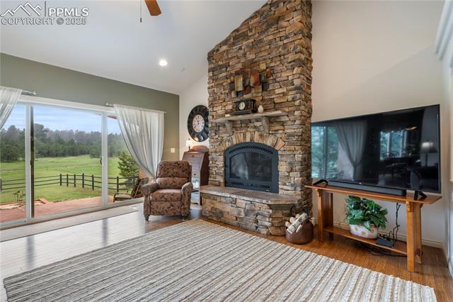 15910 Rhodes Place Elbert, CO 80106 - Photo 23 of 40 Living area with a stone fireplace, vaulted ceiling, ceiling fan, wood finished floors, and recessed lighting