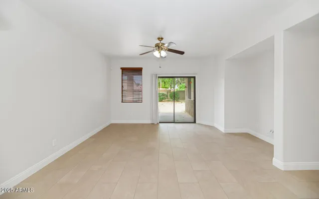 an empty room with chandelier fan and windows