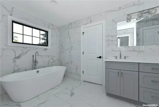 a bathroom with a tub sink and mirror