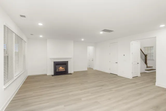 a view of an empty room with wooden floor fireplace and a window