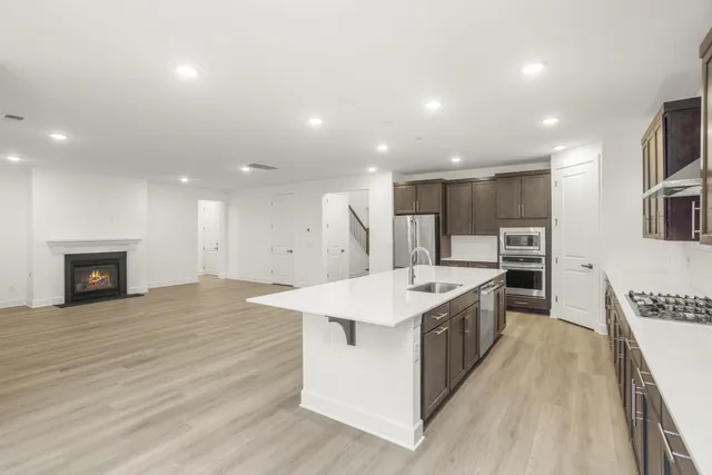 a large kitchen with stainless steel appliances a large counter top a stove and a sink