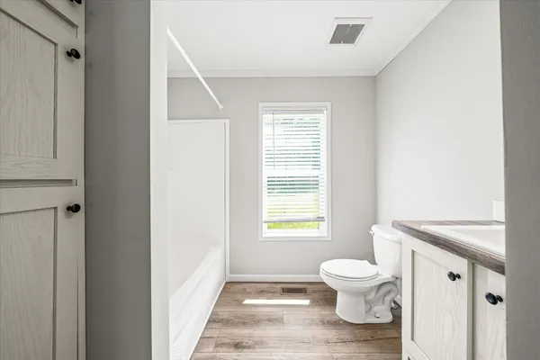 a bathroom with a granite countertop toilet a sink and a window