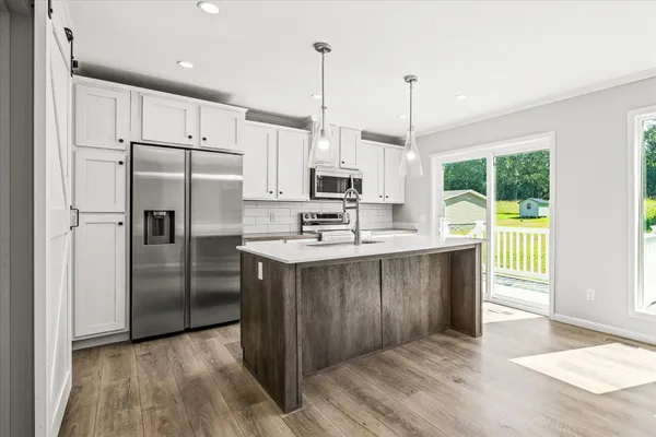 a kitchen with stainless steel appliances granite countertop a refrigerator a sink a stove and a wooden floors