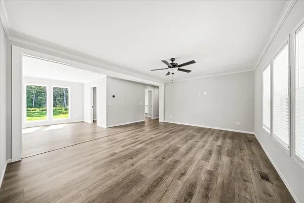 a view of empty room with wooden floor and fan