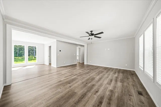 a view of empty room with wooden floor and fan