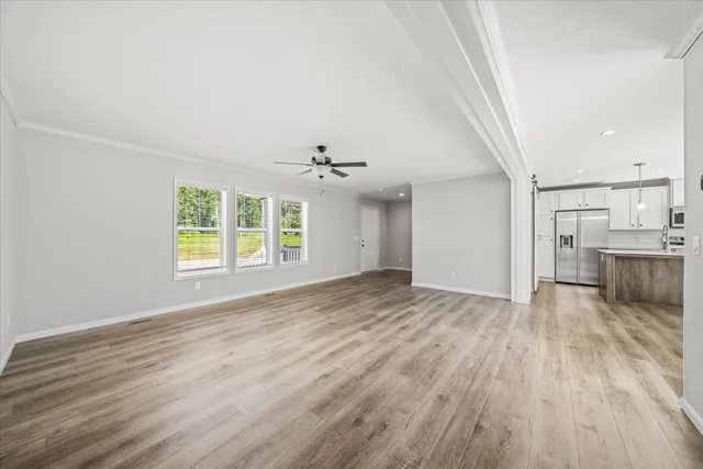 an empty room with wooden floor cabinet and windows