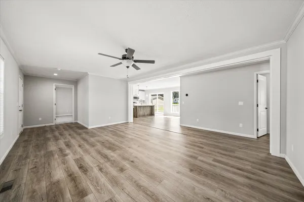 a view of empty room with wooden floor and ceiling fan