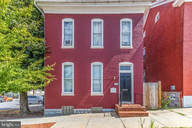 a front view of a building with red door and a tree