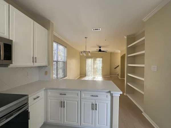 a kitchen with white cabinets and window
