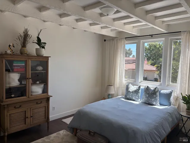 a bedroom with a bed and a potted plant on the dresser