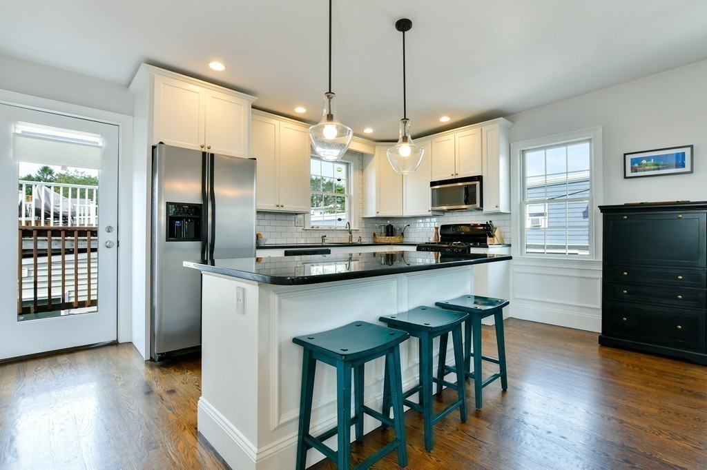 155 H Street, Unit 2 Boston, MA 02127 - Photo 7 of 20 a kitchen with stainless steel appliances granite countertop a refrigerator a stove a sink a dining table and chairs with wooden floor