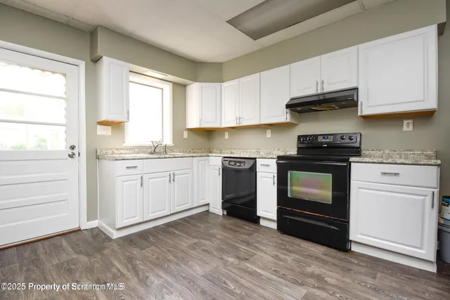 a kitchen with stainless steel appliances granite countertop a stove a sink and white cabinets