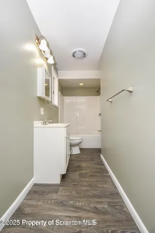 a view of a hallway with a white cabinet and wooden floor