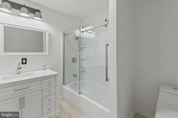 a bathroom with a bathtub shower sink vanity and toilet