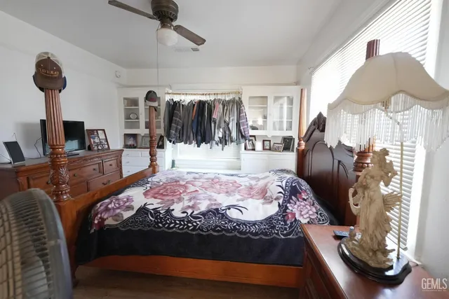 a bedroom with a bed a couch and a flat tv screen on the dresser