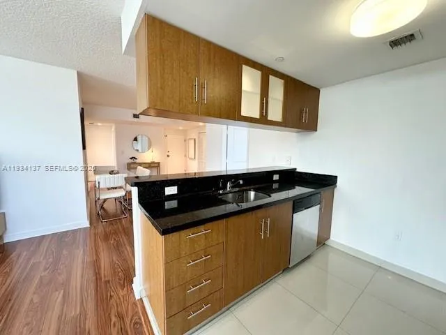 a kitchen with stainless steel appliances granite countertop a refrigerator a stove and a sink with wooden floor