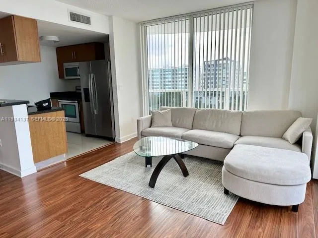 a kitchen with stainless steel appliances granite countertop a stove a refrigerator a sink a dining table and chairs with wooden floor