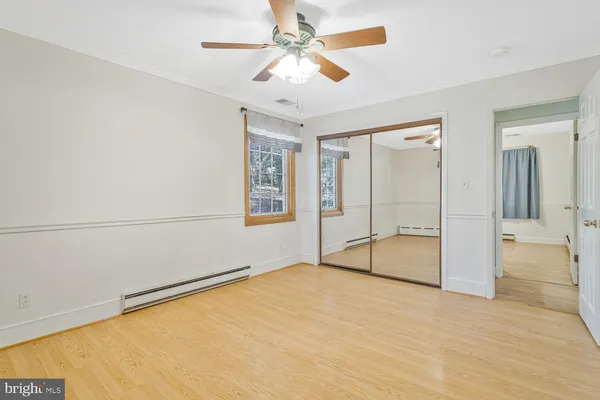 an empty room with chandelier fan and windows