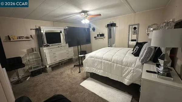 a white bed sitting in a room next to a window with pc on the table