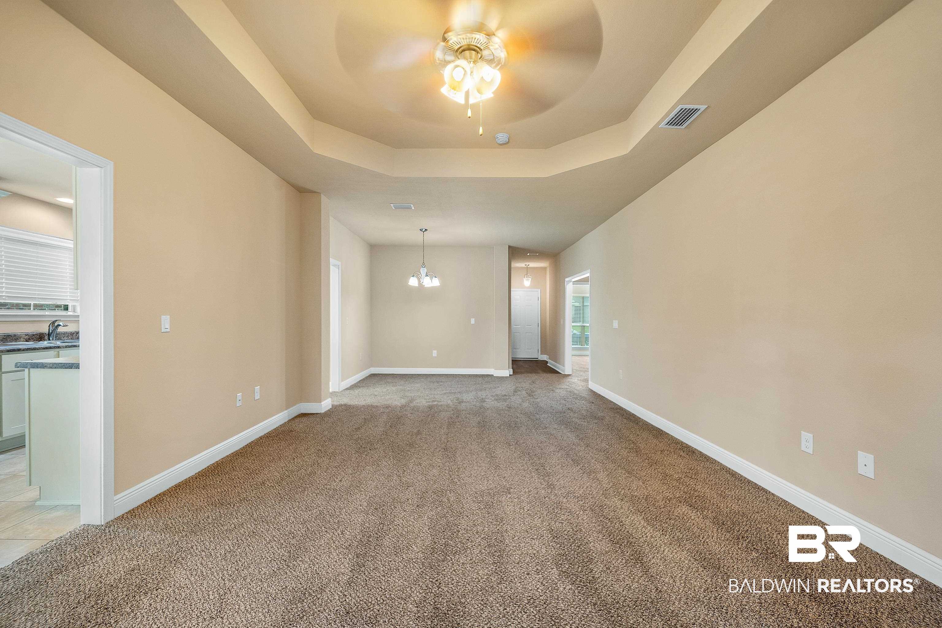 22631 Lake South Drive Foley, AL 36535 - Photo 6 of 25 Carpeted spare room with ceiling fan with notable chandelier and a raised ceiling