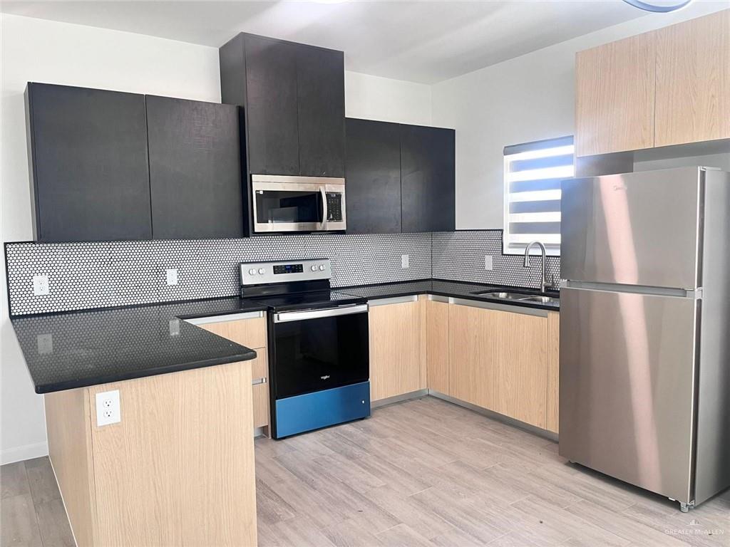 3904 Ventura Avenue, Unit 1 Edinburg, TX 78541 - Photo 10 of 12 Kitchen with a sink, appliances with stainless steel finishes, a peninsula, light brown cabinets, and dark countertops