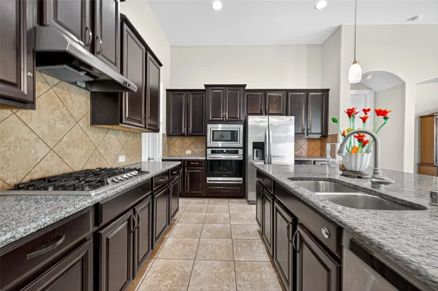a kitchen with granite countertop a sink stove and refrigerator