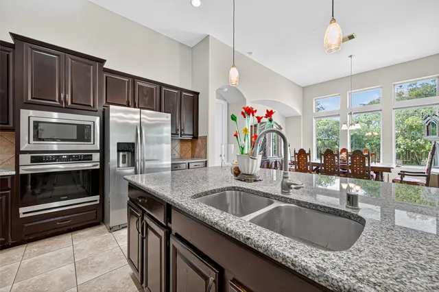 a kitchen with granite countertop a sink a counter top space and living room view