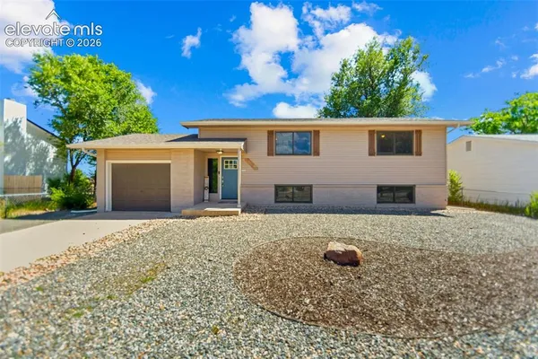 a view of a house with a backyard and a tree