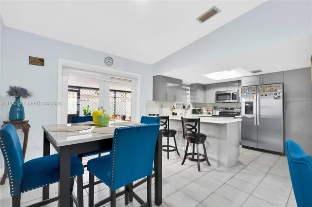 a kitchen with a dining table chairs and refrigerator