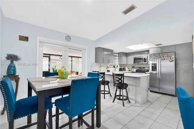 a kitchen with a dining table chairs and refrigerator