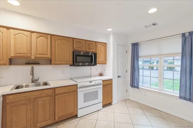 a kitchen with stainless steel appliances granite countertop white cabinets a sink and a window