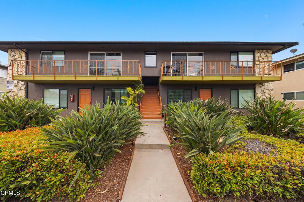 a front view of a house with glass windows and plants
