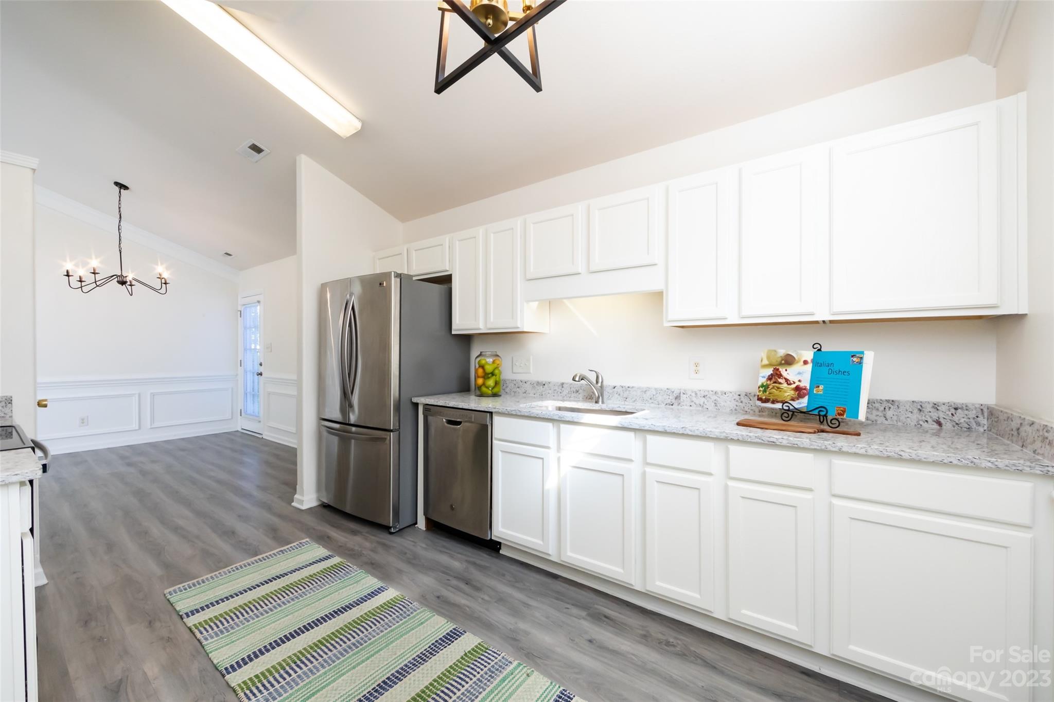 13009 Beddingfield Drive Charlotte, NC 28278 - Photo 16 of 32 a kitchen with a sink dishwasher a refrigerator and white cabinets with wooden floor