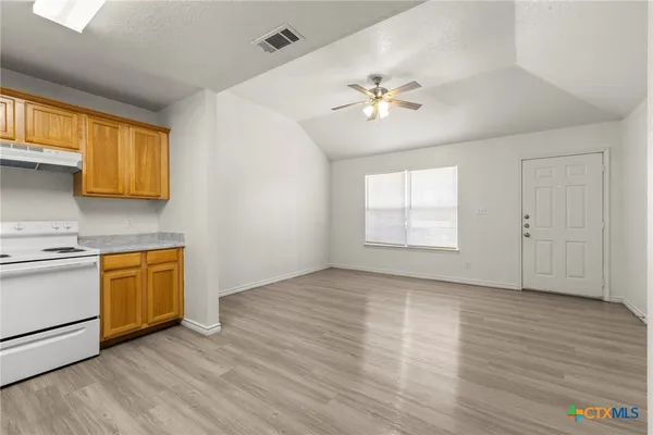 a view of an empty room with a window and wooden floor