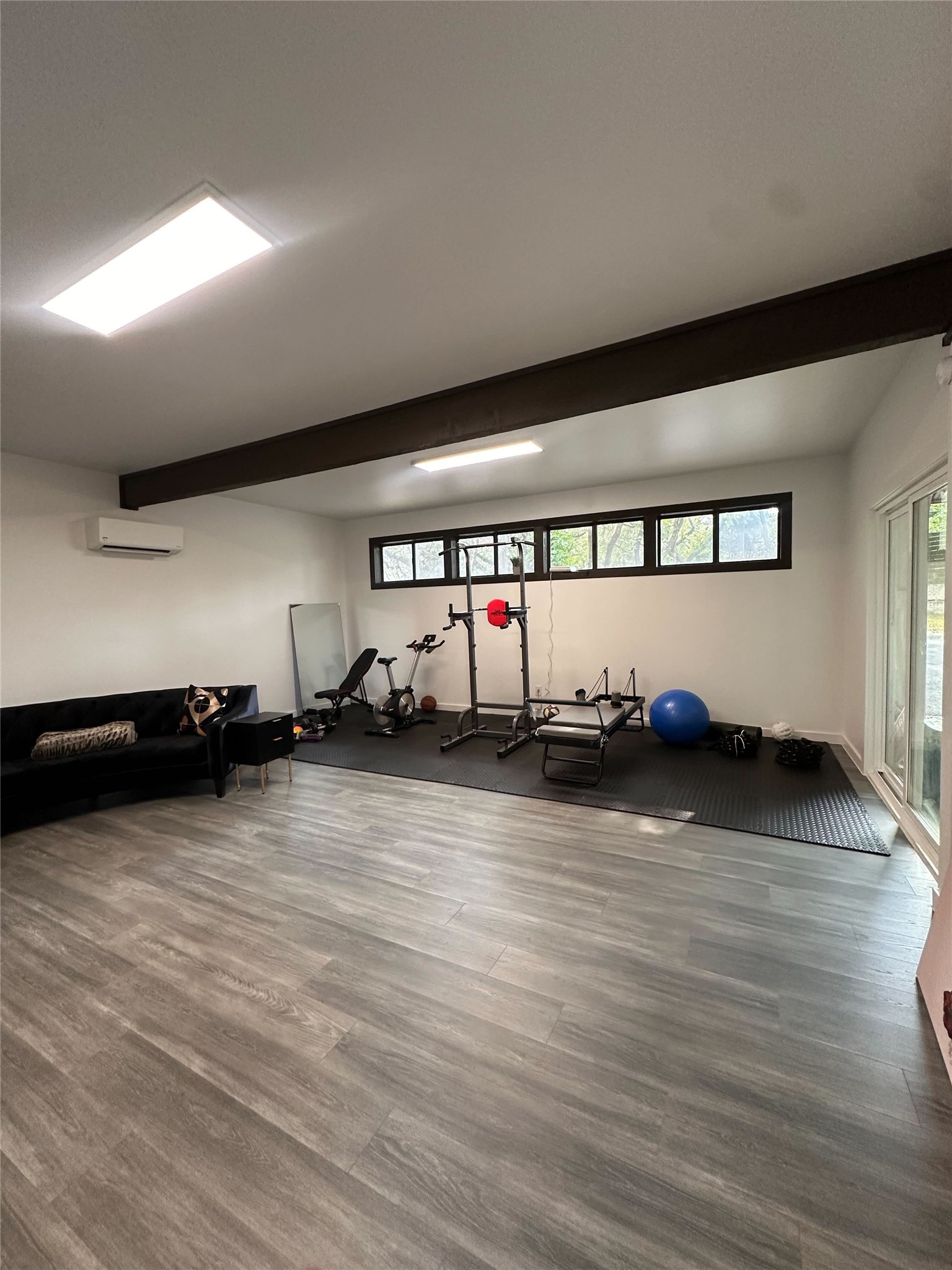 1302 Ridgecrest Drive Austin, TX 78746 - Photo 7 of 19 Exposed support beams and wood-look flooring anchor this versatile recreation space with sliding glass doors.