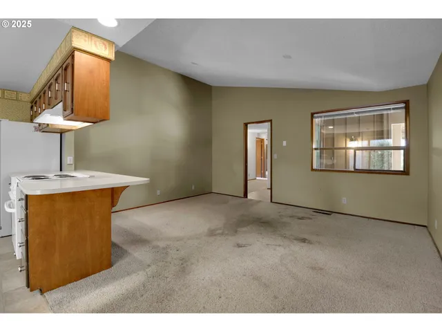 a view of an empty room with cabinet and a window