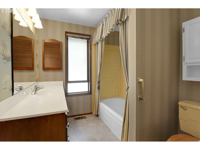 a view of a big room with windows and chandelier fan