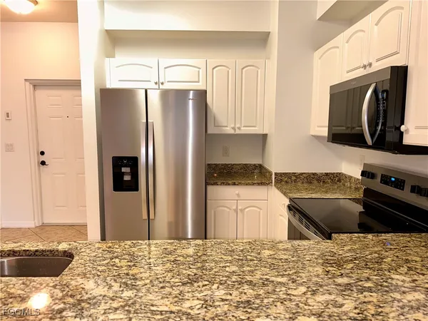 a kitchen with granite countertop a refrigerator stove and sink
