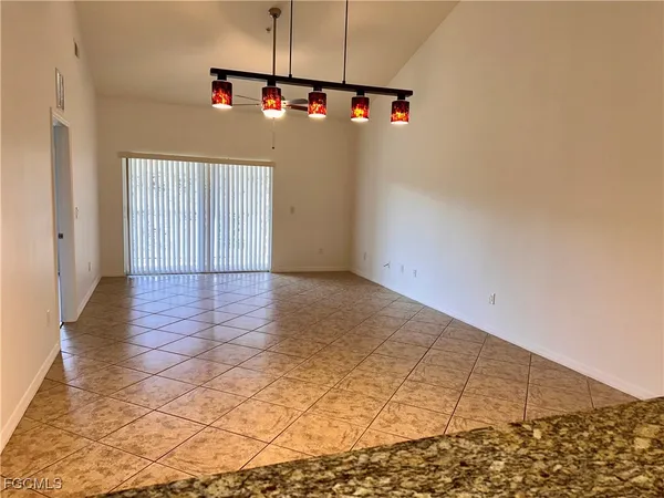 an empty room with kitchen view and wooden floor