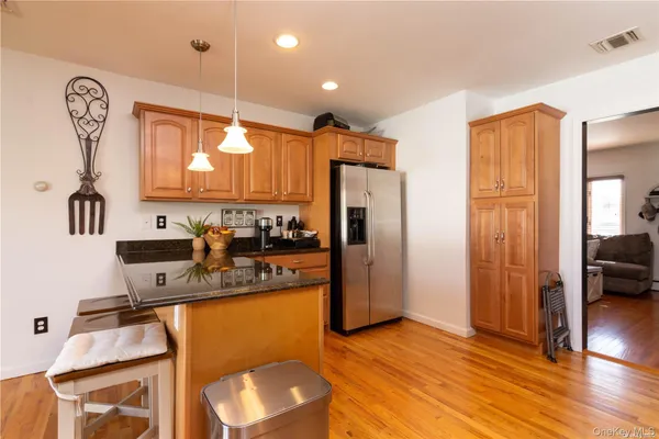 a kitchen with stainless steel appliances granite countertop a refrigerator a stove and a sink with wooden floor