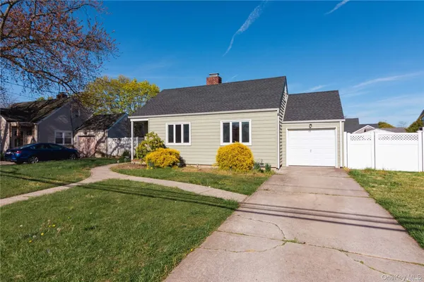 a front view of house with yard and trees in the background