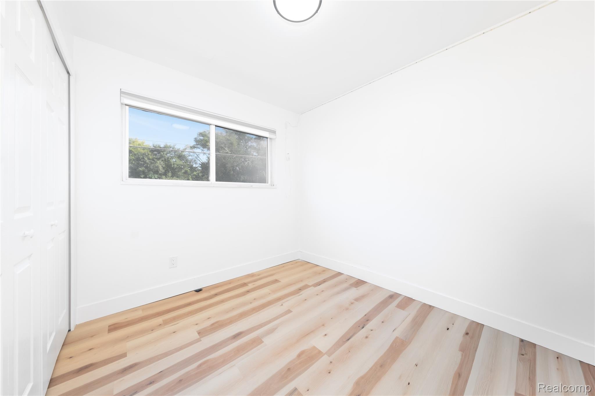 3065 South Commerce Road, Unit 9 Walled Lake, MI 48390 - Photo 11 of 15 Wood-finish flooring, white walls, and a single window with a roller shade