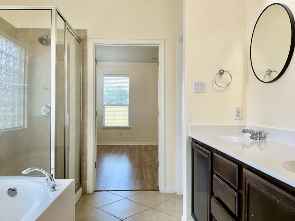 2946 Todd Trail Round Rock, TX 78665 - Photo 18 of 31 Bathroom with a stall shower, double vanity, light tile patterned flooring, a bath, and crown molding
