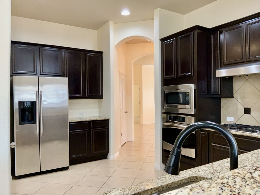 2946 Todd Trail Round Rock, TX 78665 - Photo 8 of 31 Kitchen with stainless steel appliances, arched walkways, light tile patterned floors, light stone counters, and recessed lighting