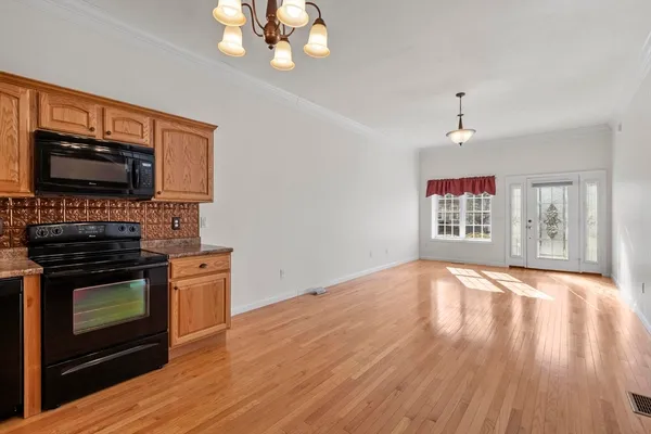 an empty room with wooden floor windows and cabinet